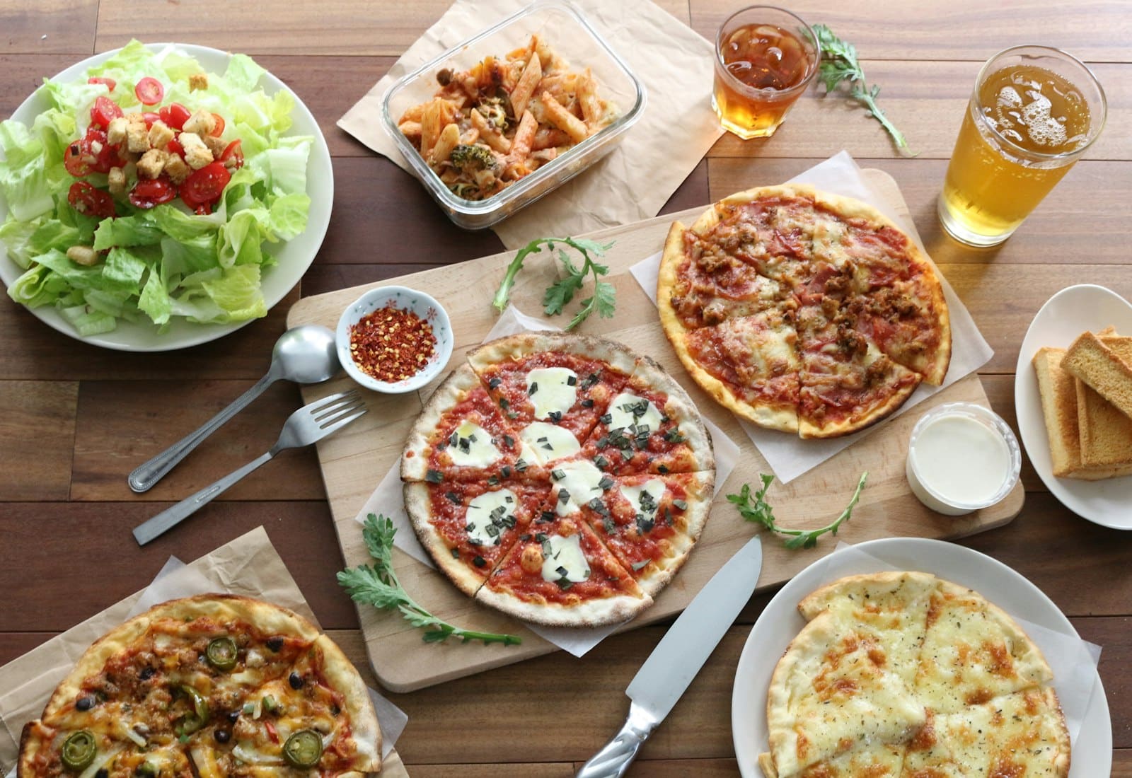 A shared table photographed from above — pizzas, salad, side dishes and drinks